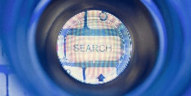Search button viewed through a lens, symbolising digital marketing and SEO strategies for enhancing online presence.