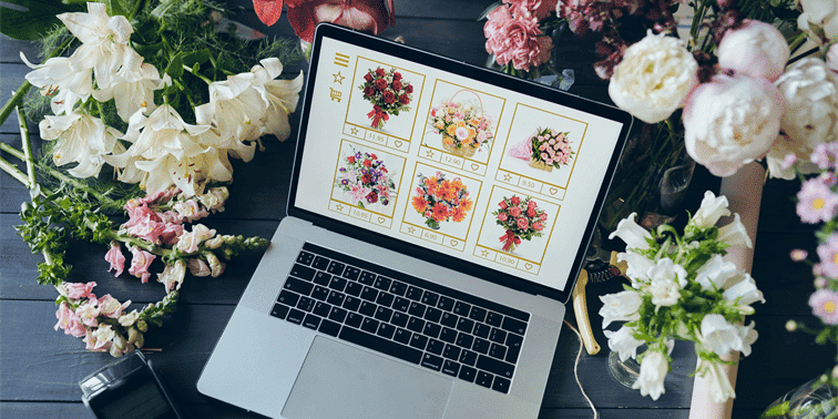 Laptop displaying an online flower shop with various bouquets and arrangements, surrounded by fresh flowers, illustrating digital marketing and e-commerce for floral businesses.