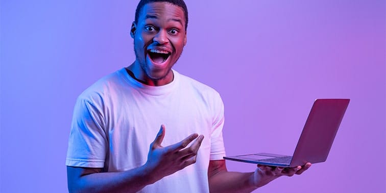 Excited man holding a laptop, showcasing digital marketing potential, with vibrant purple background.