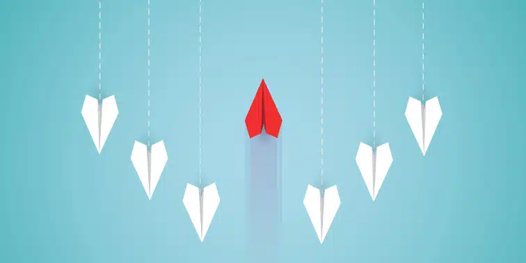 Red paper plane leading white paper planes, symbolising innovation and success in digital marketing strategies.
