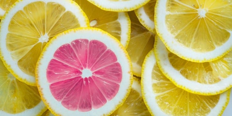 Pink grapefruit slice surrounded by yellow lemon slices, highlighting vibrant citrus colours and freshness, relevant to digital marketing themes of visibility and appeal.