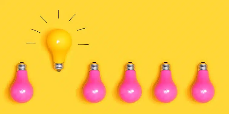 Yellow background with a central yellow light bulb illuminated among five pink light bulbs, symbolising creativity and innovative website design ideas for local businesses.