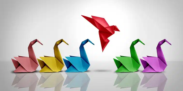 Origami birds in various colours, with a bright red bird prominently flying above, symbolising standing out in digital marketing.