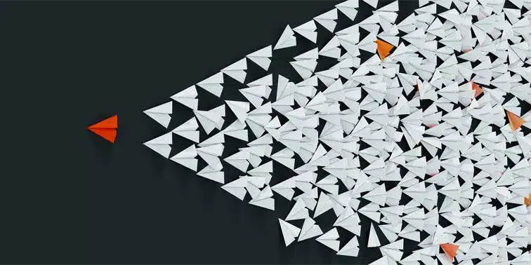 Red paper airplane leading a group of white paper airplanes, symbolising innovative digital marketing strategies and business growth.